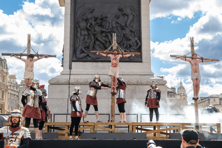 The Passion of Jesus in Trafalgar Square on Good Friday: Roman centurions erecting three crucifixes with people strapped to them, in front of the base of Nelson's Column in Trafalgar Square
