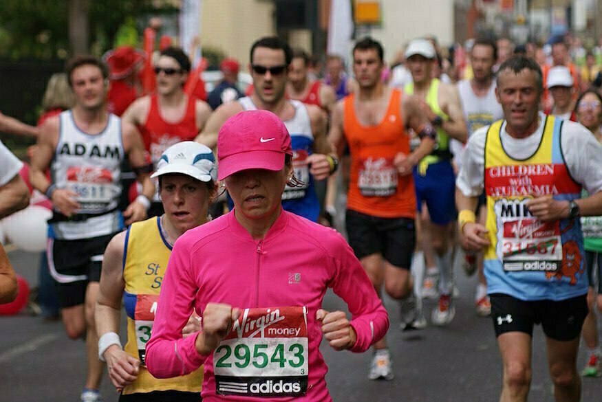 London Marathon 2026: A woman in pink running top and hat running the London Marathon, with other runners also taking part behind her.
