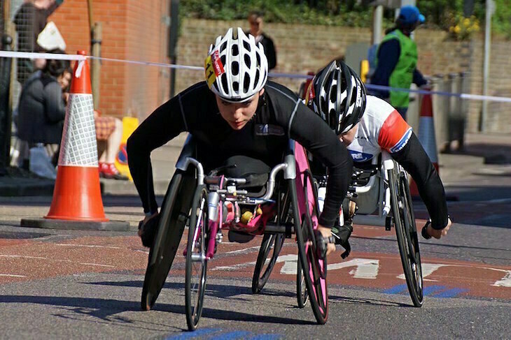 London Marathon 2026: Wheelchair racer Jade Jones taking part in the London Marathon on  a road on part of the course in the Isle of Dogs, with a second wheelchair racer close behind her