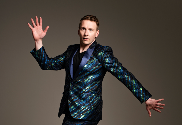 What's on in London this weekend: Joe Lycett posing for a photo in a sparkly green and blue jacket