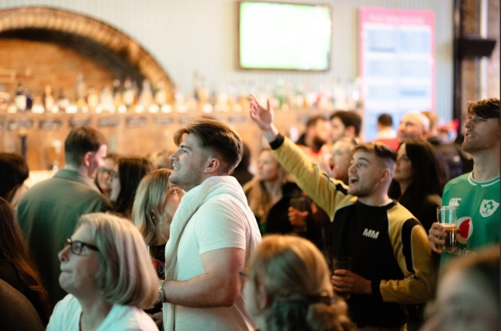 Top events in London today: people sitting and standing in a pub watching a screen