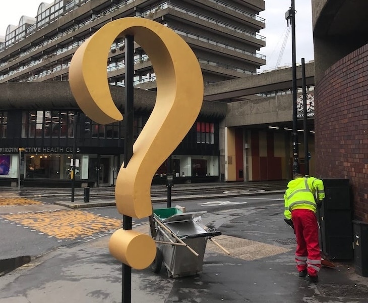 A street sweeper near the Barbican in London, with a giant question mark sculpture beside him