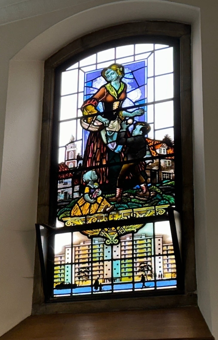 نافذة من الزجاج الملون في Christ Church Blackfriars تظهر فيها امرأة تحمل سلة ومسكنًا في ميدان نيلسون