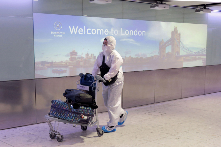 Someone pushing an airport trolley, wearing a hazmat suit