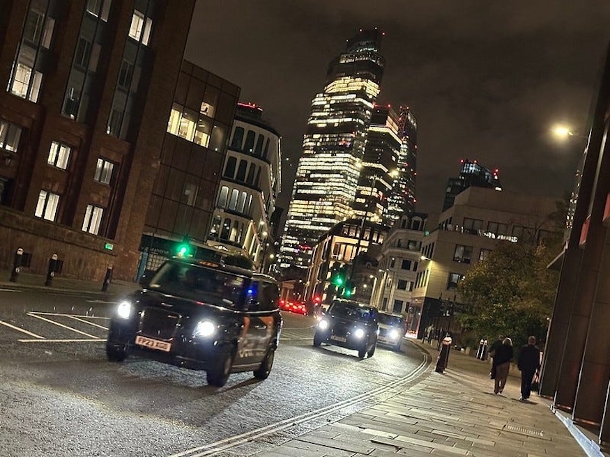 A taxi driving through the City of London at night