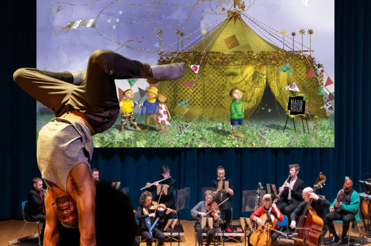The best things to do in London this weekend: a performer doing a handstand in front of an orchestra and a large TV screen