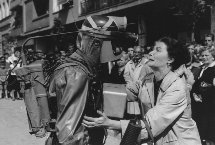 Top events in London today: a black and white photo of a woman crying while holing a person in a gas mask and suit