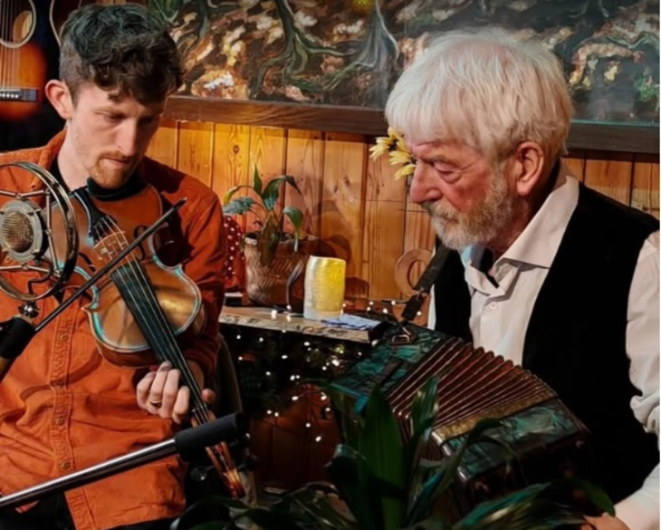 Things to do in London today: a young man playing the fiddle sitting next to an older man playing the accordion