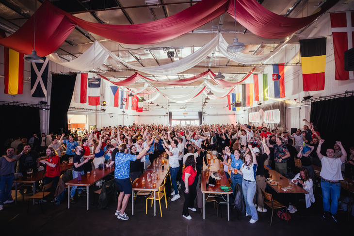 People celebrating in a huge beer hall festooned with flags