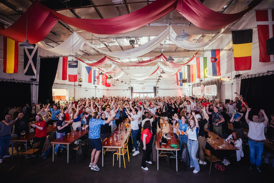 People celebrating in a huge beer hall festooned with flags