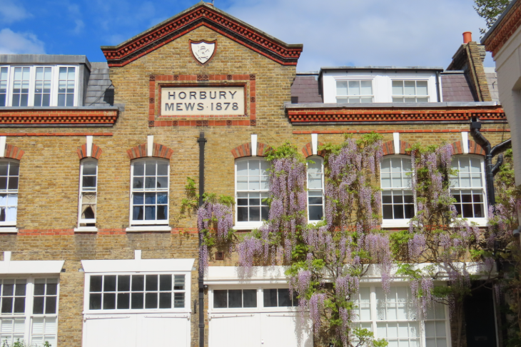 Wisteria walking route in London mapped: a brick building with pale wisteria draped around the first floor windows on the right hand side