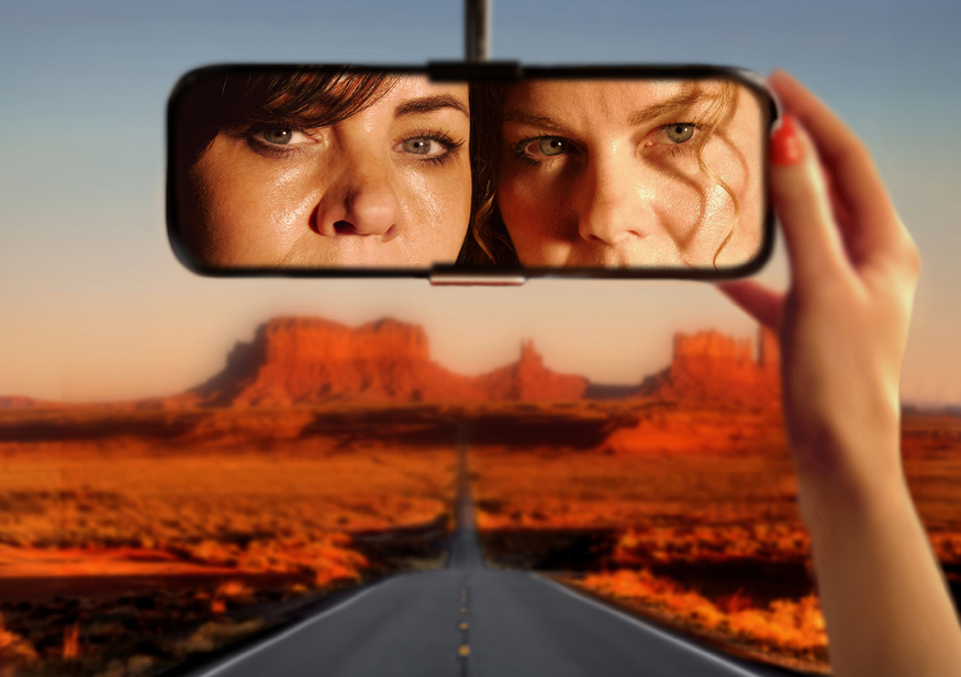 Two women looking into a a rear view mirror