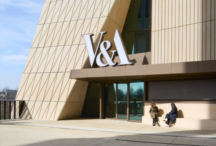 Free events in London: two people sitting on a bench outside the entrance to the new V&A East