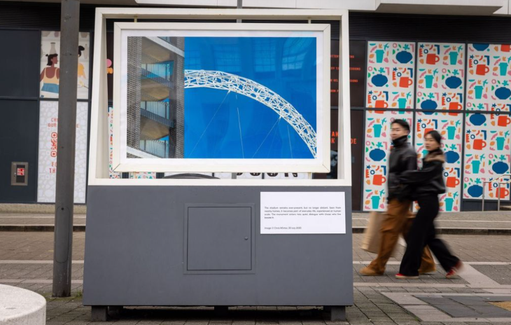 Free events in London this week: two people walking past a large scale photo of part of the Wembley Arch