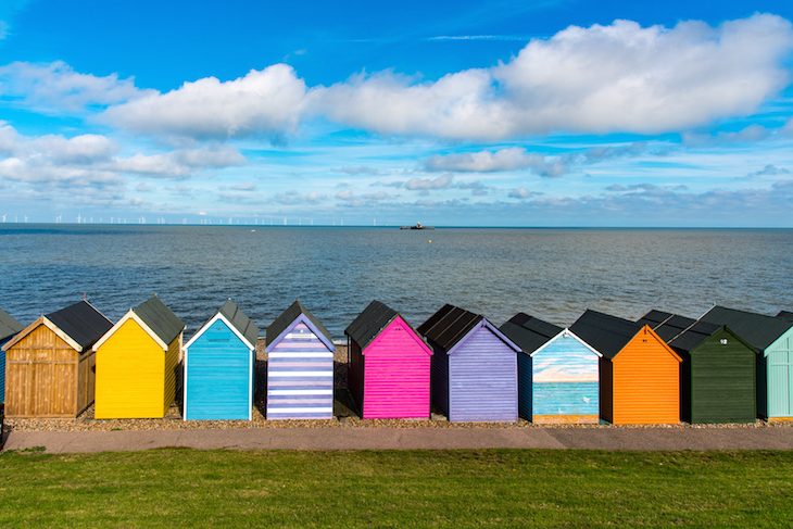 Seaside towns in Kent: a row of colourful beach huts along the seashore