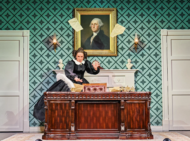 Fourth July/Independence Day 2026 in London: a woman throwing papers around on a desk beneath a portrait of Abraham Lincoln