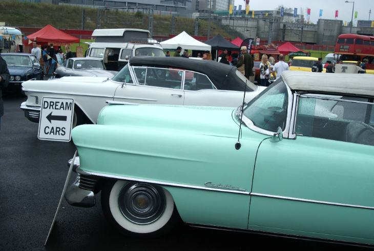 Top events in London this weekend: A light green vintage Cadillac convertible parked in the foreground of an outdoor car show, with a white classic car and a "Dream Cars" sign behind it.