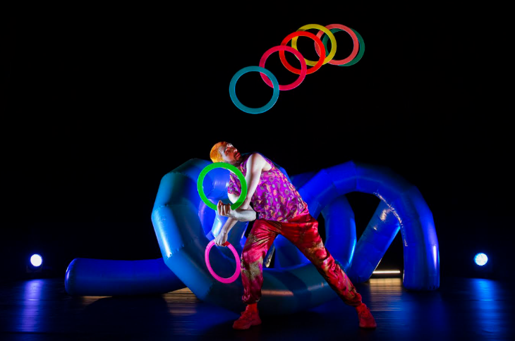 Things to do in London today: a performer juggling colourful neon rings on stage