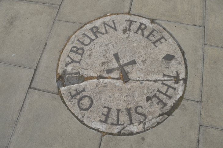 What's on in London today: A circular stone plaque set into a sidewalk with metal lettering that reads 