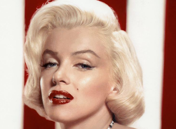 Fourth July/Independence Day 2026 in London: A glamorous close-up portrait of Marilyn Monroe with her signature platinum blonde hair, red lipstick, and a diamond and emerald necklace, posed against a red and white striped background.