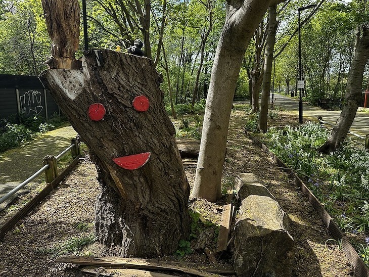 A tree with a painted on face and some rubber ducks in Itchycoo Park, Beckton