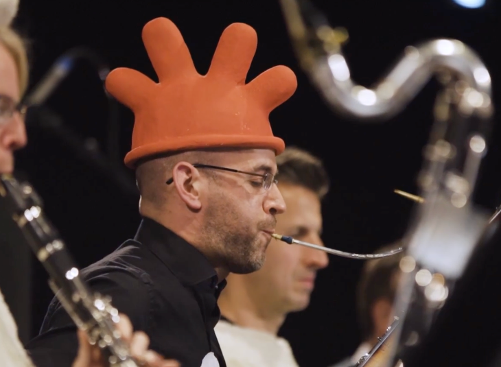 Top things to do in London in May 2026: a man wearing a hat to resemble the penguin from Wallace and Gromit, playing a wind instrument as part of an orchestra