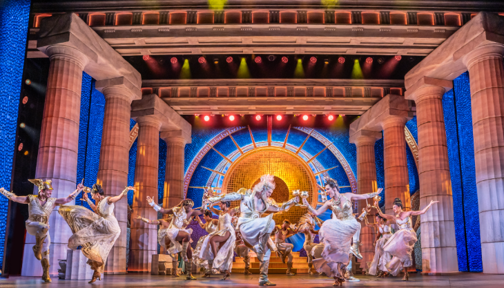Best family/children's theatre shows in London for summer 2026: the cast of Hercules dancing in sync in a temple set