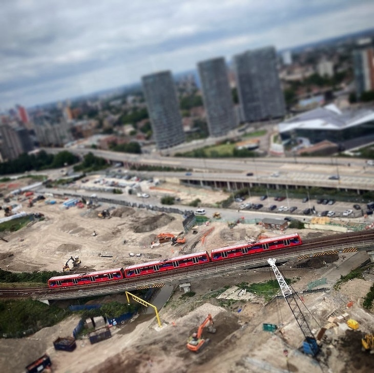 A tilt-shift image of a DLR train snaking across a development site
