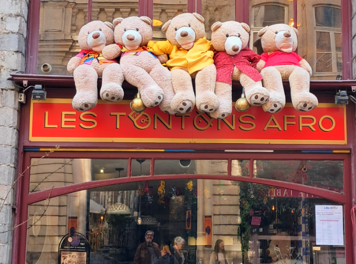 Day trip to Lille from London: a row of giant teddy bears sitting atop a restaurant sign reading "Les Tontons Afro"