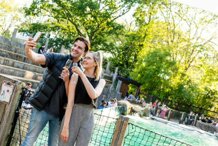 Things to do in London in summer 2026: a couple with champagne glasses by the penguin pool at London Zoo