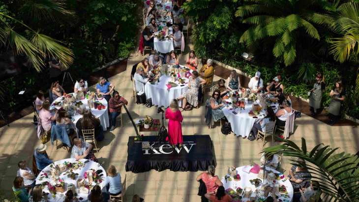 Things to do in London today: people sitting a tables with craft materials around a central speaker in a conservatory at Kew Gardens