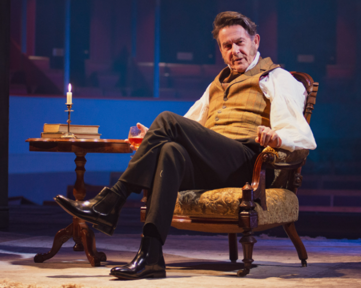 Adrian Lukis sitting in a chair in his role as Mr Wickham