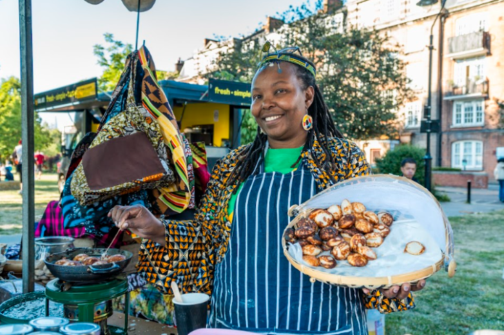 Things to do today in London: a woman cooking and holding up a plate of food