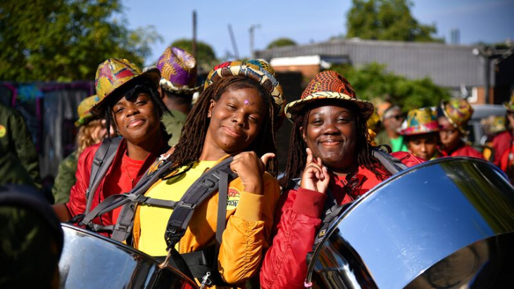 Top events in London in July 2026: Members of Kinetika Bloco smiling while wearing harnesses holding steel pans
