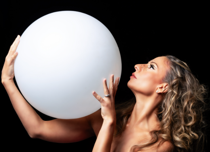 A woman holding a large white orb close to her face