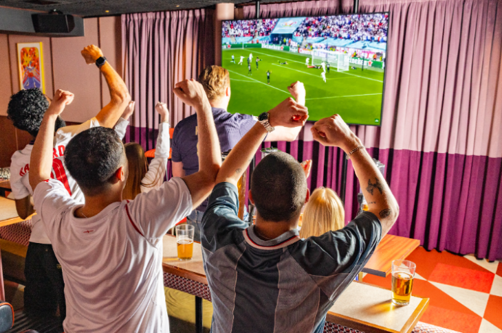 Free screenings of Wimbledon 2026 matches in London: people in a bar cheering while watching football on a screen