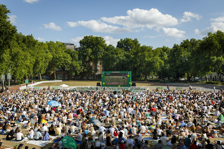 Crowds of people watching tennis on a large screen