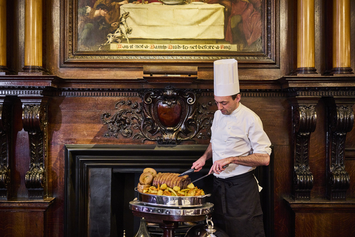A chef carving beef from a trolley