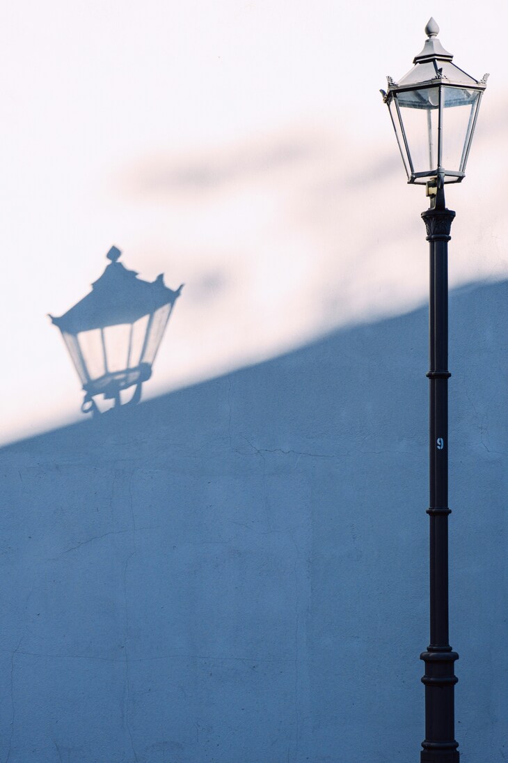 A vintage lamppost casts a shadow on a wall.. Image: <a href="https://unsplash.com/photos/a-vintage-lamppost-casts-a-shadow-on-a-wall-po_vDnm4D_8" target="_blank" rel="noopener noreferrer">Yuri Krupenin</a>