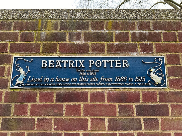 Beatrix Potter's London: A blue rectangular commemorative plaque on a brick wall for Beatrix Potter, featuring illustrations of Peter Rabbit and Jemima Puddle-Duck. The text states she was a writer and artist who lived on the site from 1866 to 1913.