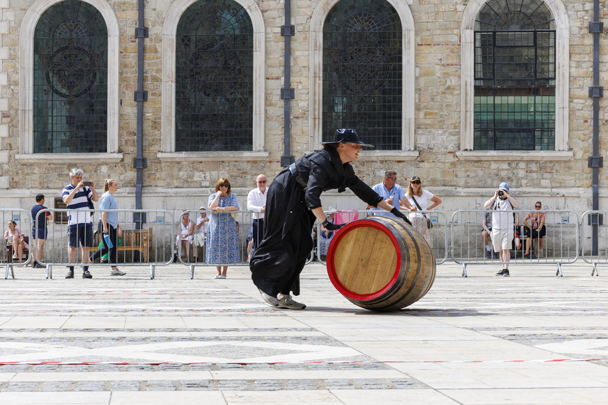 Someone wearing all black, rolling a cask