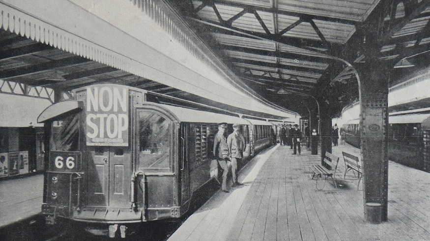 A vintage photo from 1911 of an underground train at Golders Green station. It carries a prominent sign on the front saying 'Non Stop'
