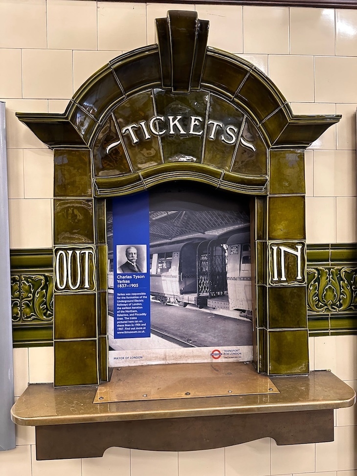 An ornate ticket office window in Hampstead. It is closed and has an information board about Charles Tyson Yerkes in place of the glass.