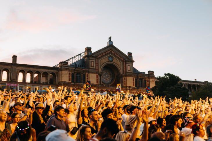 Things to do in London today: a festival crowd with their arms in the air outside Buckingham Palace