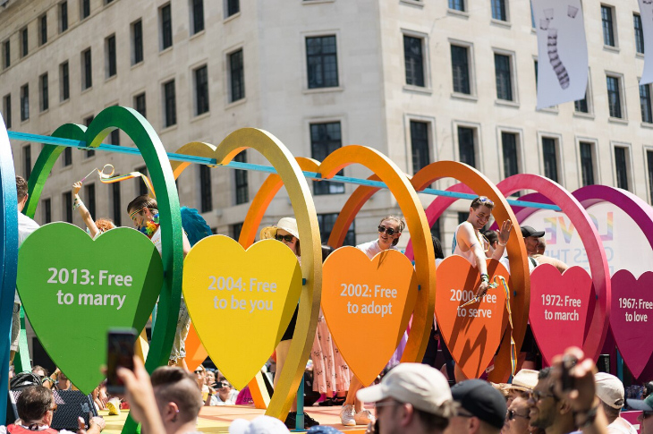 What's on in London this weekend: A colorful Pride parade float features a series of large, rainbow-colored heart arches. Each arch contains a smaller heart-shaped sign displaying a milestone year in LGBTQ+ rights, such as 