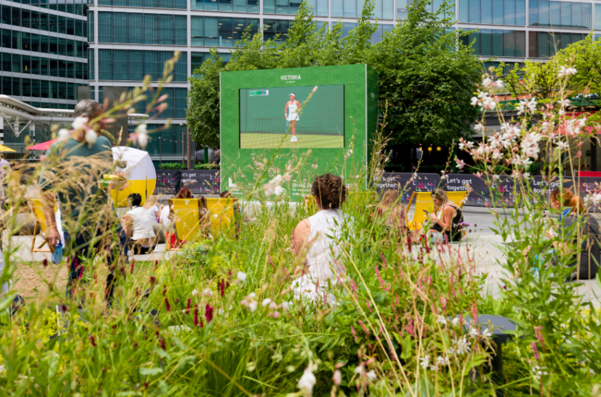 A large screen in a garden showing tennis