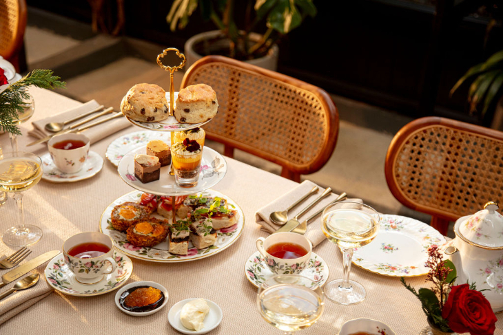 Where to have afternoon tea in London: a table set for afternoon tea, with delicate tea cups filled with tea, alongside a tiered stand holding several food items