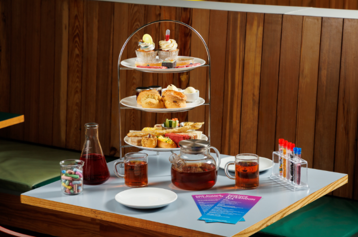 Where to have afternoon tea in London: A table set for with an afternoon tea stand, plus several pipettes and other pieces of scientific equipment.