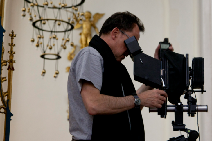 A photograph of a man looking into a camera inside a church