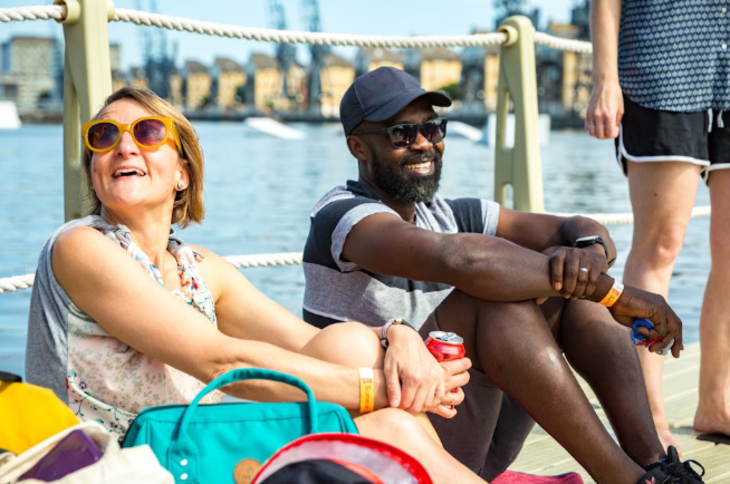 Two people sitting on the boardwalk over the water in the Docks